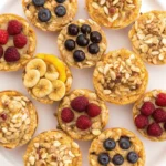 Easy 4-Ingredient Baked Oatmeal Cups in a muffin tin with raspberries and chocolate chips.