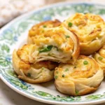 Golden-brown Herb and Cheese Puff Pastry Swirls on a baking sheet.
