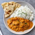 Creamy homemade butter chicken in a skillet, served with basmati rice and fresh cilantro.